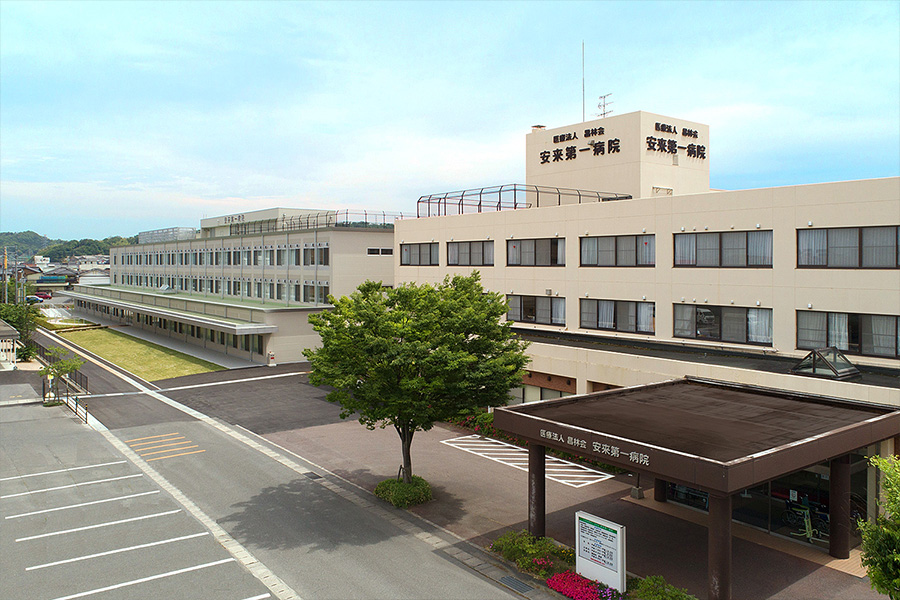 安来第一病院の広角外観。複数棟の医療施設建物と駐車場が見える。