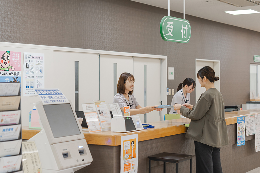 介護施設の受付カウンター。スタッフが来訪者対応をしており、受付業務の様子が見られます。